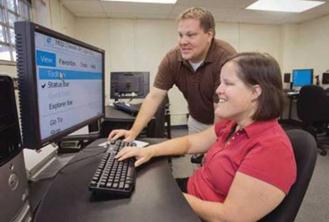 Description: A man and a woman are working at a computer. The text on the monitor is magnified.