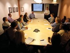Description: A group of people meet around a conference table.